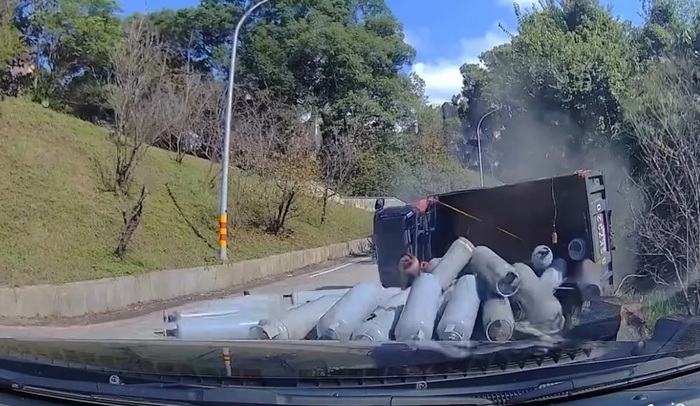 貨車向後倒退後，右後輪撞上路邊緣石導致整輛車翻覆，車上的瓦斯鋼瓶也散落一地。（圖／Threads @truly_man_ivan授權提供圖片